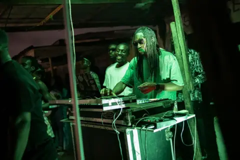 OLYMPIA DE MAISMONT / AFP A DJ plays music from decks, illuminated by green lights - Sunday 29 September 2024