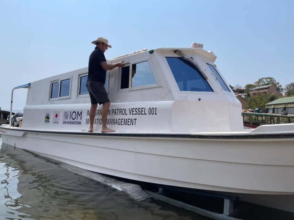Immigration Patrol Vessel, IPV 001, Lake Malawi boat, UN Migration, IOM, Japan aid, marine security, patrol boat, man inspecting boat, white patrol vessel, migration management, lakeside security, Malawi marine transport, small security vessel