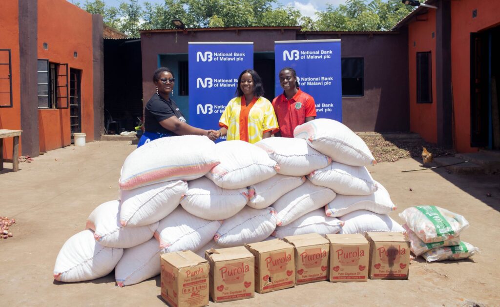 selemani(left) handing over the food items to mbale(middle) and chawinga (left) (002)