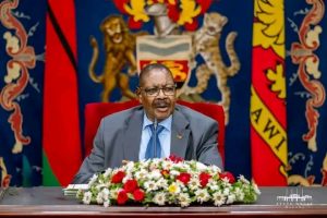 Ayuba Praises Mutharika’s Leadership, Describes Him as Deeply Thoughtful 2 Man seated at formal event backdrop