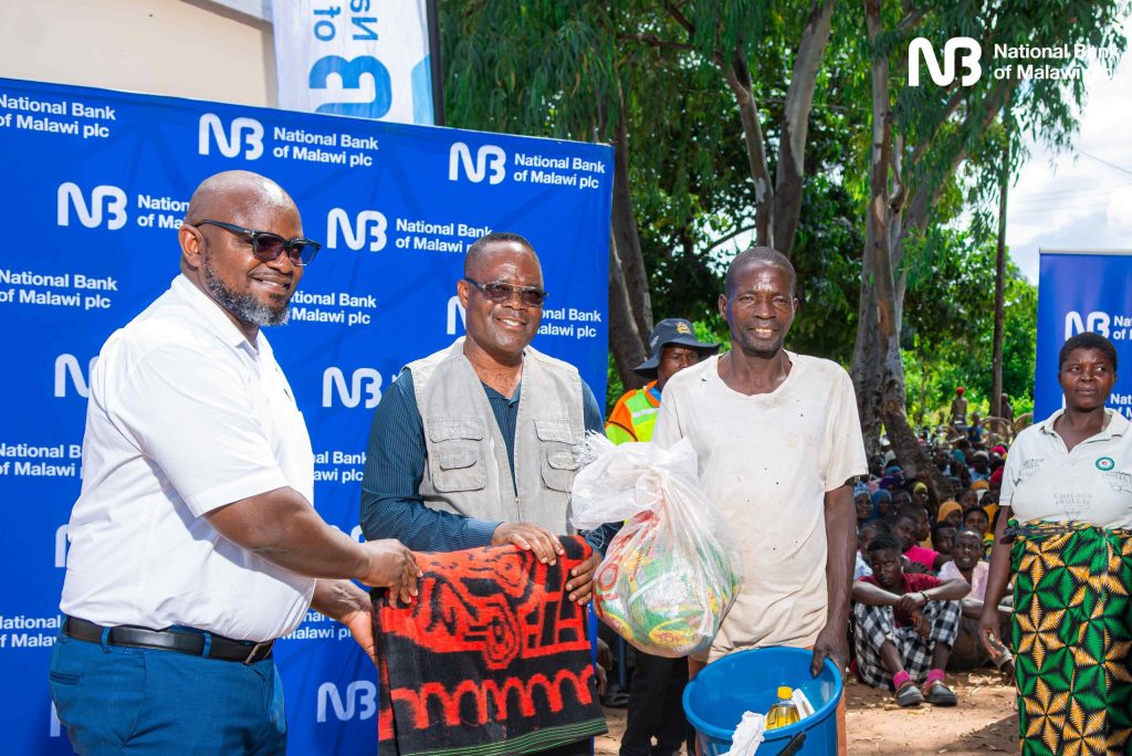 Ulaya left and Chidiwa centre hand over donated items to a flood victim 002