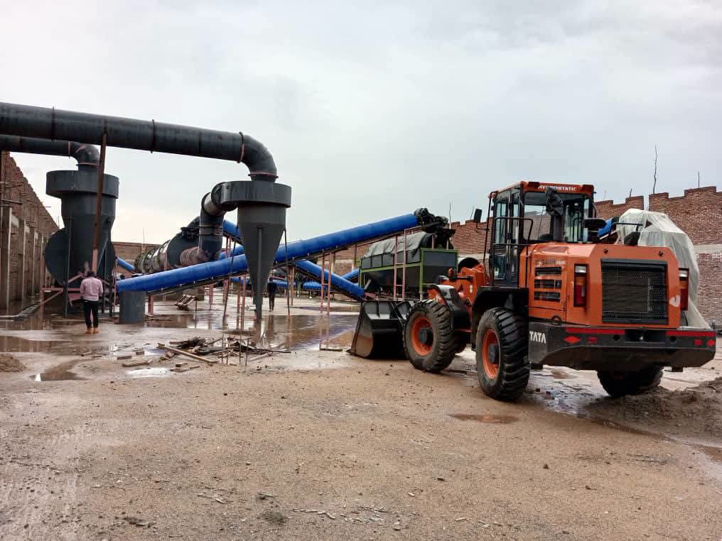 Industrial machinery and an orange front-end loader at the fertilizer manufacturing plant in Dowa