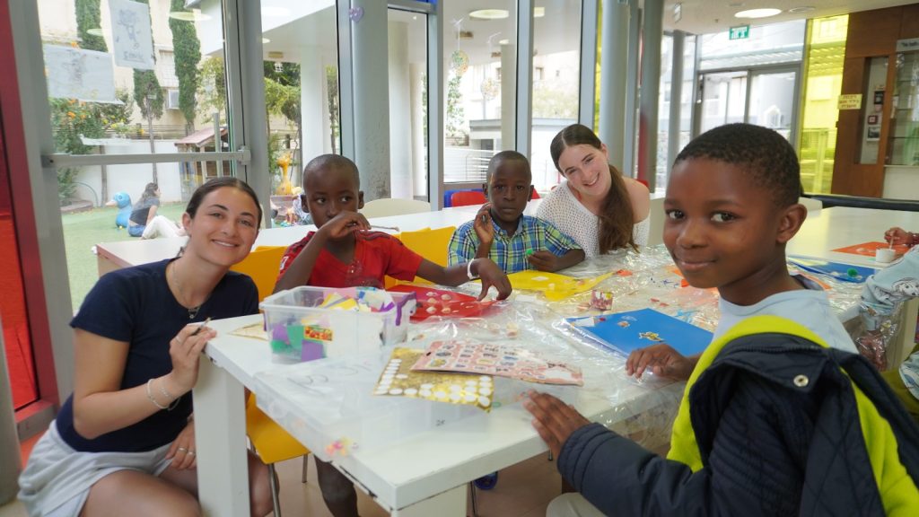 Malawian children and Save a Child’s Heart volunteers smile while doing arts and crafts together in Israel