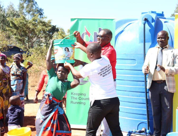 Msimuko in red aiding a woman carry water 002
